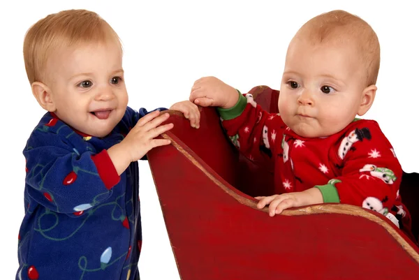 Two toddler boys in winter pajamas in a sleigh — Stock Photo, Image