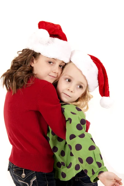 Two cute caucasian girls in santa hats hugging Stock Image