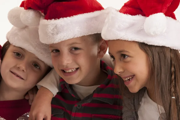 Trois enfants en chapeaux de Père Noël souriant — Photo