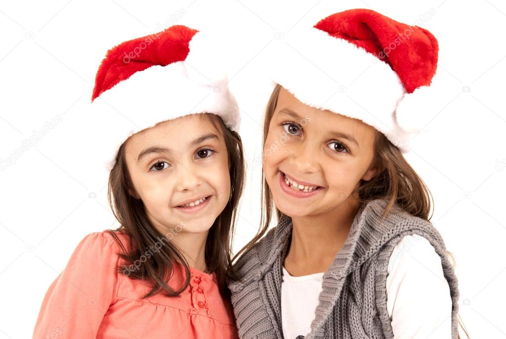 two young adorable sisters wearing santa hats