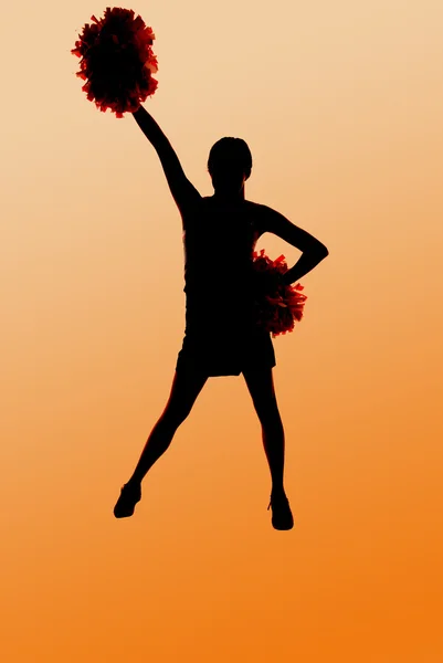 Silhouette of a young cheerleader with an orange background — Stock Photo, Image