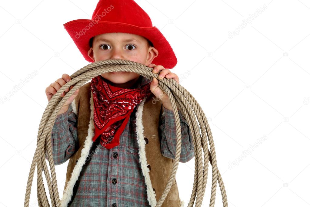 playful very young cowboy wearing red hat and holding a rope