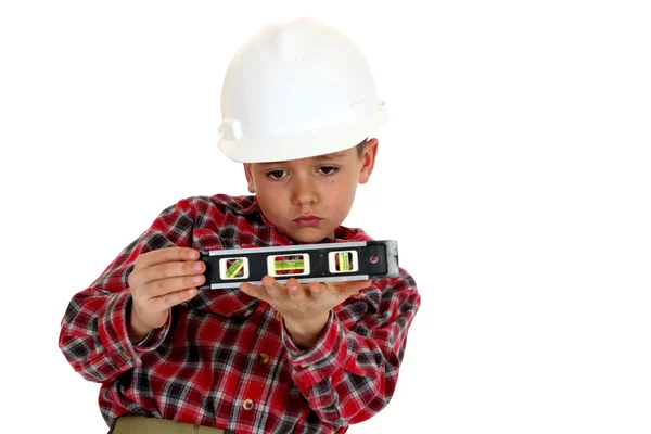 Jeune garçon portant un casque dur tenant un niveau — Photo