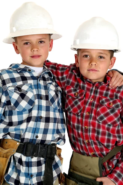 Zwei junge Brüder mit Harthüten und Werkzeuggurten umarmen sich — Stockfoto