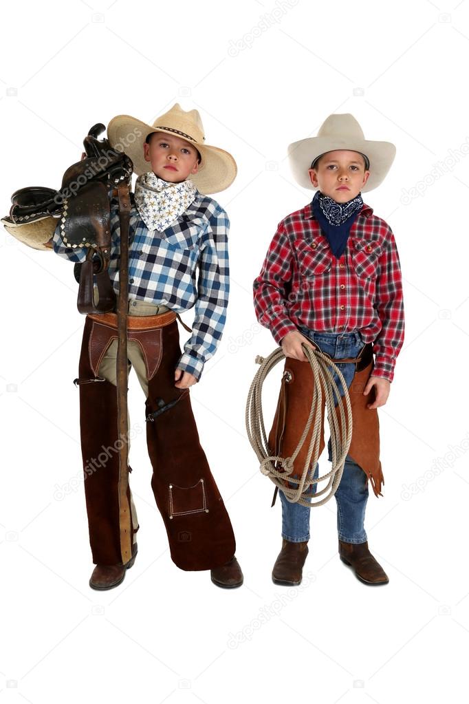 two young cowboys holding a saddle and a rope