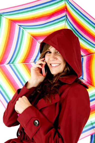 Female model talking on cellphone holding colorful umbrella — Stock Photo, Image