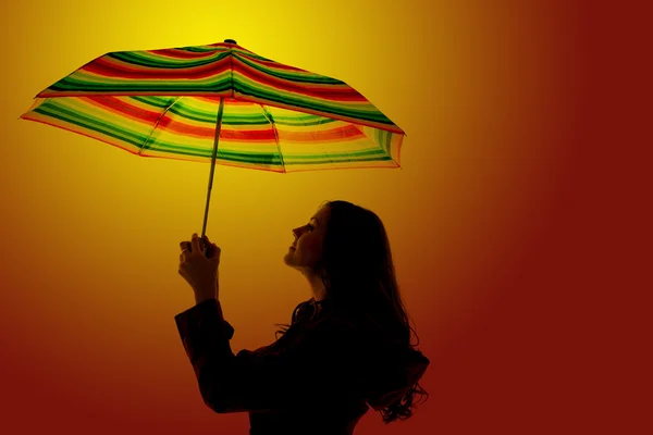 Silueta de una mujer que aguanta un paraguas colorido con una naranja —  Fotos de Stock