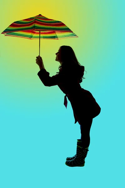 Cute pose and silhouette of a woman holding an umbrella blue bac — Stock Photo, Image