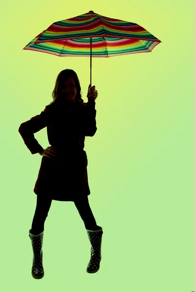 Silhouette of a woman holding a colorful umbrella with green bac — Stock Photo, Image
