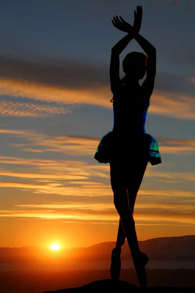 Силуэт балерины, стоящий в пуанте на фоне заката — стоковое фото