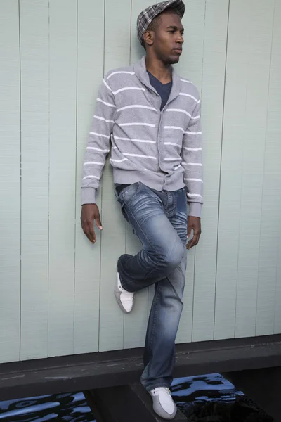 Zwarte mannelijke model leunend tegen een groene houten muur — Stockfoto