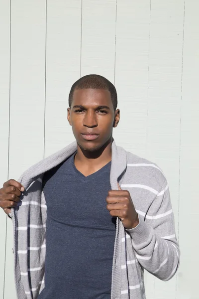 Attraktiv svart manlig modell håller hans randiga tröja — Stockfoto