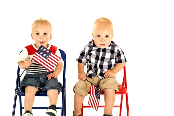 Dos lindos chicos rubios sosteniendo banderas americanas sentados —  Fotos de Stock