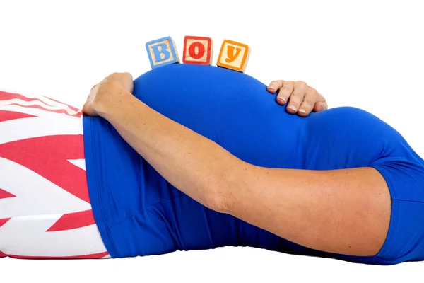 Mulher grávida deitado com blocos de madeira soletrando menino sobre ela — Fotografia de Stock