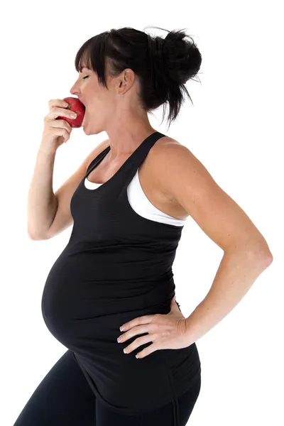 赤いリンゴを食べる妊娠中のフィットネス モデルの側面図 — ストック写真