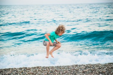 bir çocuk deniz dalgaları ile oynuyor