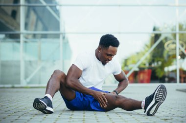 Genç Afro-Amerikan sporcusu sabah koşusunda stadyumun yakınında spor yapıyor.
