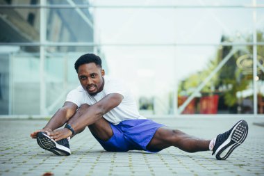 Genç Afro-Amerikan sporcusu sabah koşusunda stadyumun yakınında spor yapıyor.