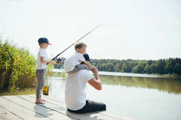 一个父亲在夏天的周末带着两个年幼的儿子在湖里钓鱼 — 图库照片