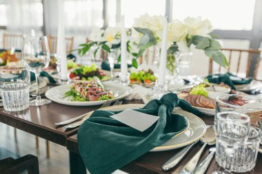 Yeşil peçeteler ve mumlarla süslenmiş bir düğün masası.