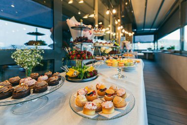 Düğün töreninde farklı renklerde lezzetli tatlılar ve açık büfe masası.