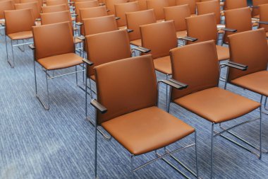 Müzayededen önce turuncu sandalyeli boş bir konferans odası.