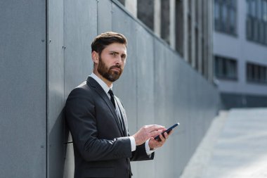 Beyaz sakallı, şehir merkezindeki ofis binasında çalışan, mesajlaşan, iyi haber cep telefonu okuyan. İş adamı açık havada akıllı telefon kullanarak resmi bir takım elbiseyle mesajlaşıyor.