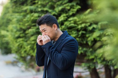 Sokakta ofisin yanında hapşıran Asyalı bir adamın alerjisi ve hastalığı var.