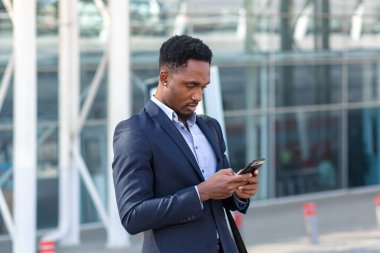 Havaalanı yakınlarında seyahat eden Afrikalı işadamı cep telefonu uygulaması kullanarak taksi çağırıyor.