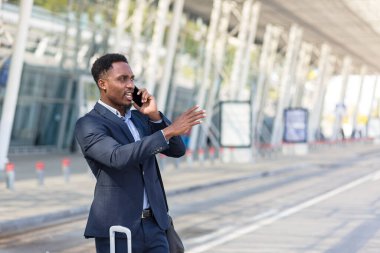 Havaalanı yakınlarında cep telefonuyla konuşan Afro-Amerikalı bir adam iş gezisine çıktı.