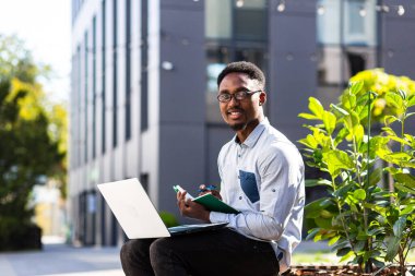 Öğrenci internetten çalışıyor, Afrikalı Amerikalı adam gülümsüyor ve seviniyor, online kurslara katılıyor, dizüstü bilgisayar kullanıyor.