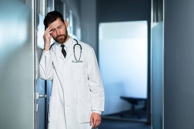 Yorgun doktor çok çalışıyor, başı çok ağrıyor, kötü hissediyor, kliniğin koridorundaki bir adam sonuçtan hayal kırıklığına uğruyor.