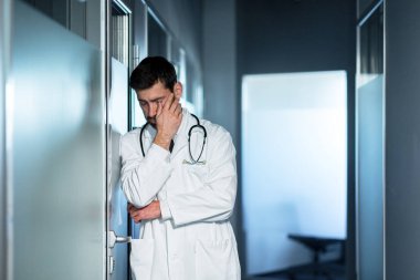 Yorgun doktor çok çalışıyor, başı çok ağrıyor, kötü hissediyor, kliniğin koridorundaki bir adam sonuçtan hayal kırıklığına uğruyor.