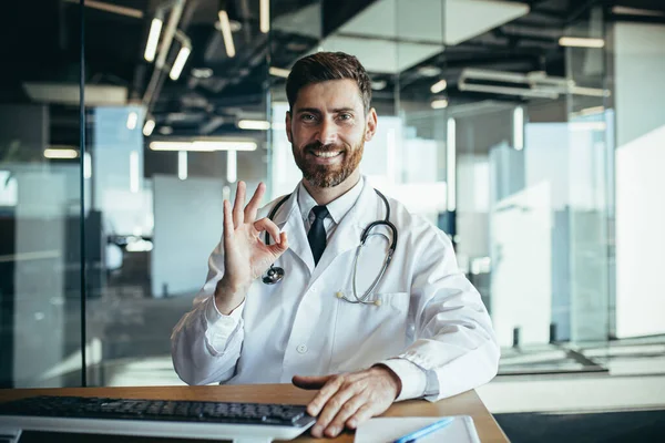 Başarılı Bir Doktor Masada Oturur Kameraya Bakar Gülümser Elleriyle Mutlu — Stok fotoğraf