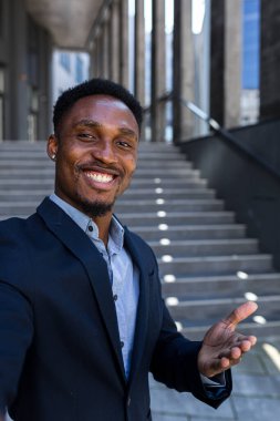 dikey görüntülü akıllı telefon kamerası Afro-Amerikan iş adamı bir video görüşmesinde ön kamera kullanarak telefonda konuşuyor. Siyah iş adamı web kamerasından konuşuyor. Takım elbiseli bir ofis çalışanının konuşması.