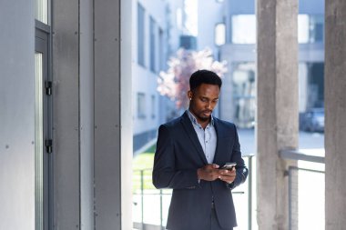 Video görüşmesi yapan Afro-Amerikalı işadamları ofis dışında telefon ve uygulama kullanıyor. Takım elbiseli, neşeli ve başarılı bir adam.