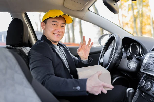 Male Courier Asian Looks Camera Smiles Holding Parcel Sitting Car — Stock Photo, Image