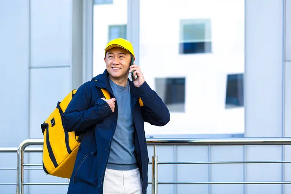 亚洲男性送餐供应商带着大包的送餐信使在电话中交谈 学习送餐地址 — 图库照片