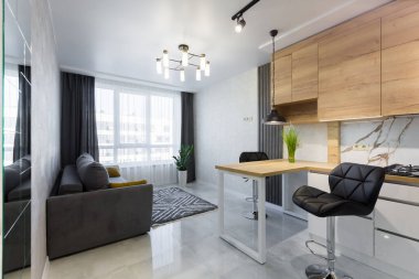 Modern bir mutfağın içinde, küçük bir dairede, ahşap eklemleri ve beyaz mermer kiremitleri olan bir bar.