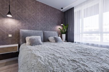 Küçük bir dairede modern tarzda geniş çift kişilik yataklı bir yatak odası.