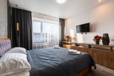 Küçük bir dairede modern tarzda geniş çift kişilik yataklı bir yatak odası.