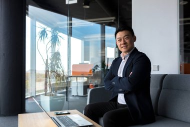 Başarılı bir işadamı olan patron kameraya bakıp gülümsüyor ve modern ofiste çalışıyor.