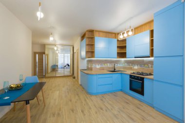 Dairesinde ahşap olan büyük mavi bir mutfak.