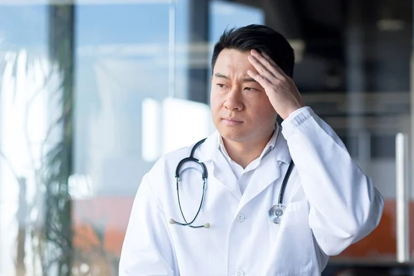 一张亚洲医生厌倦了工作的特写照片 在诊所里头疼得厉害 — 图库照片