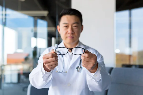 一位亚洲眼科医生为一位现代诊所的病人提供眼镜 — 图库照片