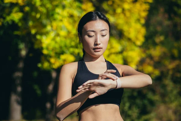 Sportowa Azjatycka Kobieta Patrząc Inteligentny Zegarek Nowoczesny Biegacza Pomocą Smartwatch — Zdjęcie stockowe