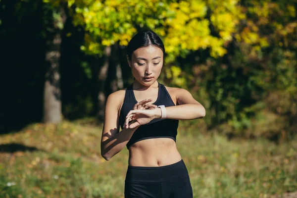 Sportowa Azjatycka Kobieta Patrząc Inteligentny Zegarek Nowoczesny Biegacza Pomocą Smartwatch — Zdjęcie stockowe