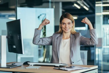 Business woman I can do everything, portrait of successful business owner, businesswoman looking at camera and smiling, working in modern office at computer, gesture of success and victory