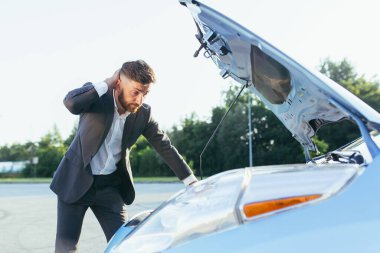 Sinirli ve sinirli bir adam, bozuk bir arabanın yanında, bir sigorta acentesini ve tamir ekibini aramaya çalışır. Araba tamiri için