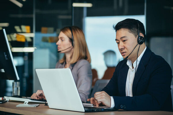 Serious support worker listens to customer, Asian man uses headset and computer for video call, support service